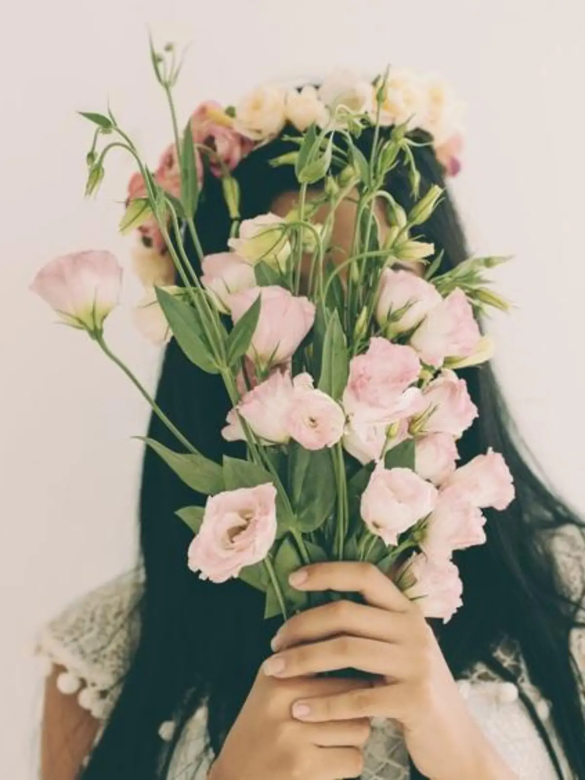 Woman holding pink flowers and hiding behind it