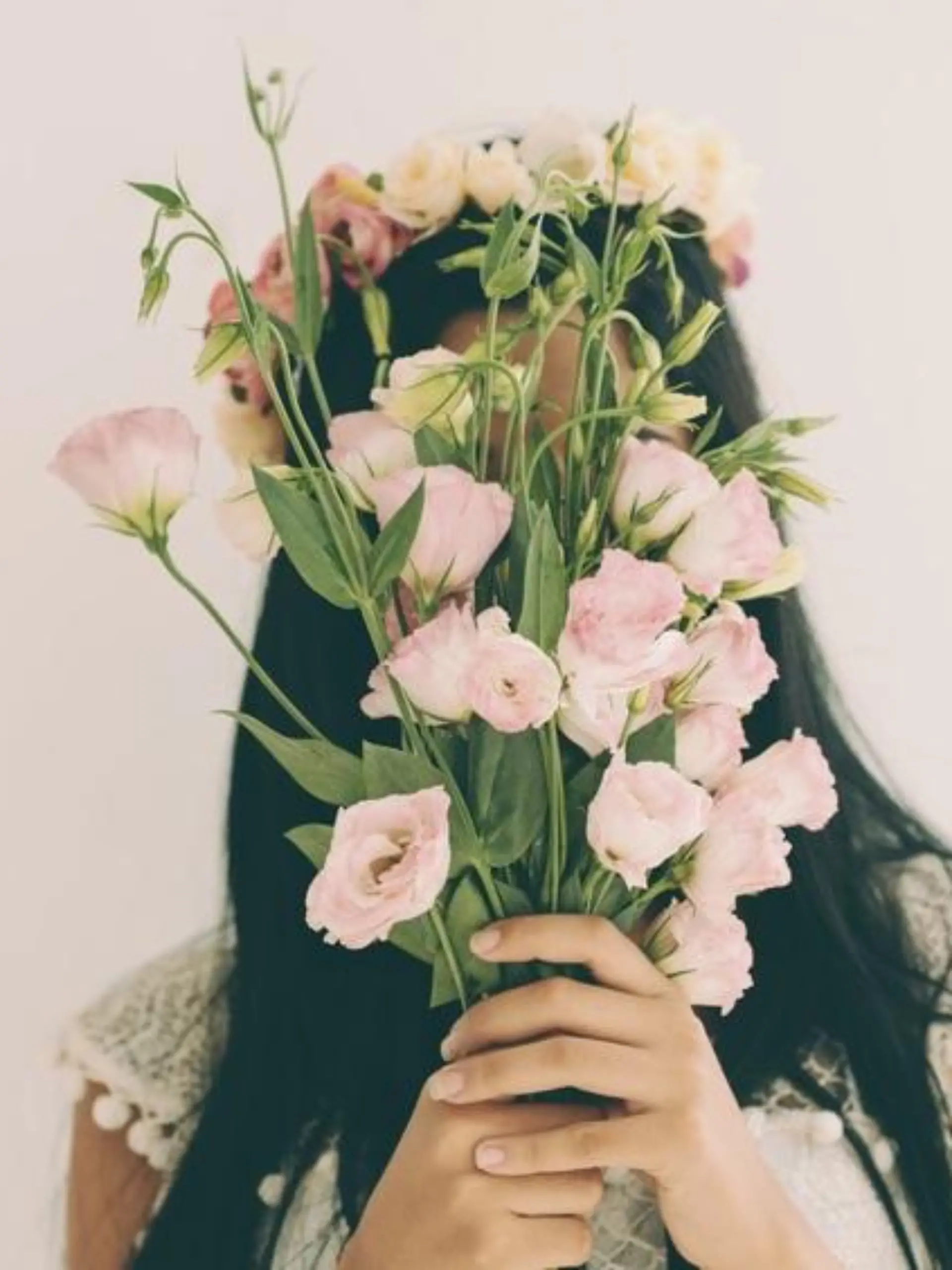 Woman holding pink flowers and hiding behind it