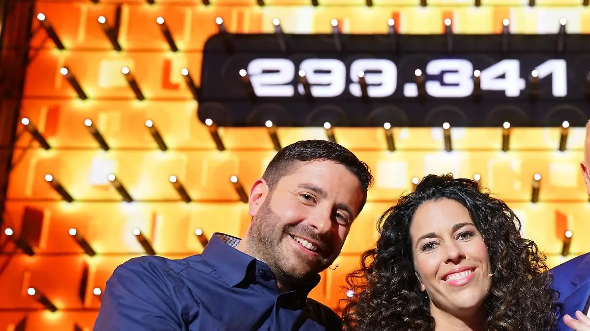 Moderator Frank Buschmann (l.) mit den Kandidaten Sabrina (37) und Basel (40) aus Meckenheim, die sich über ihren Gewinn von 299.341 Euro freuen.