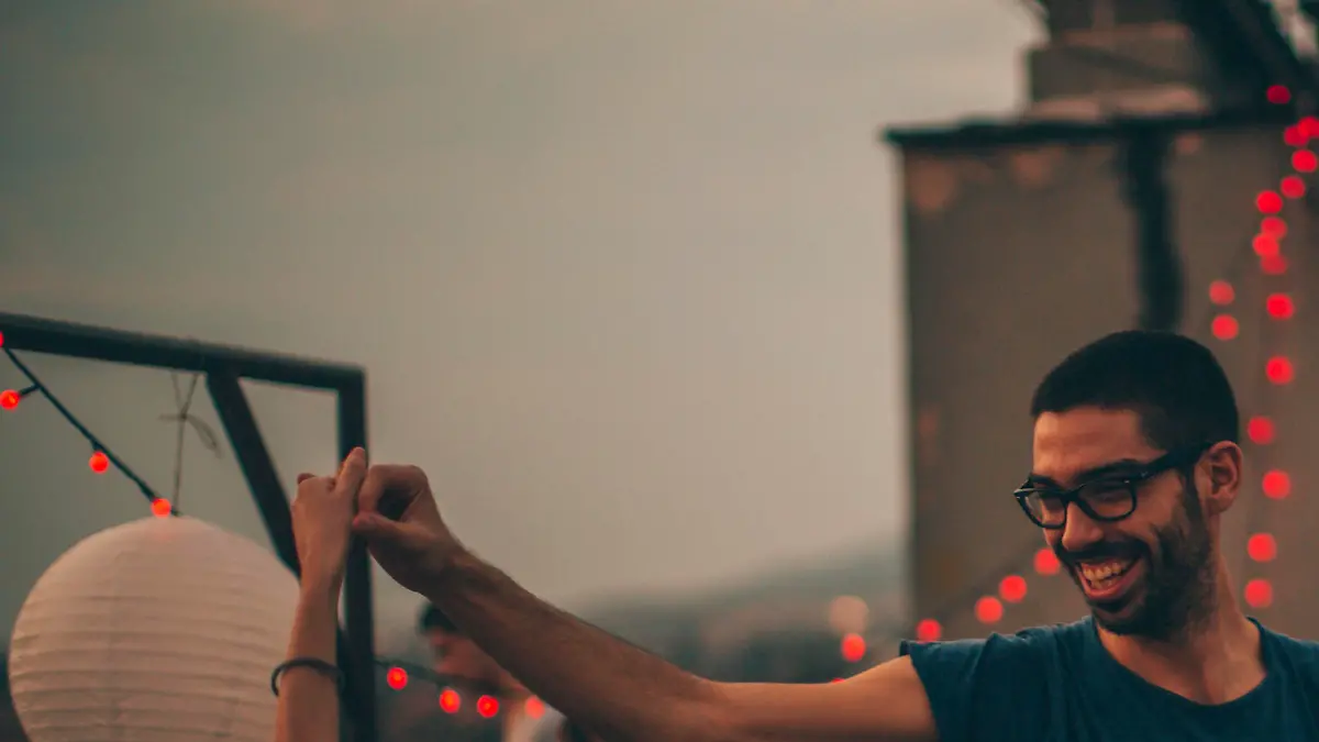 Couple of friends having a dancing party on the rooftop of the building at sunset