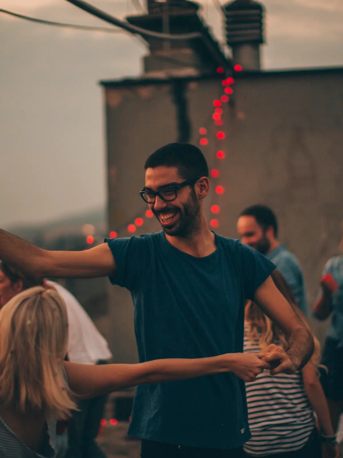 Couple of friends having a dancing party on the rooftop of the building at sunset