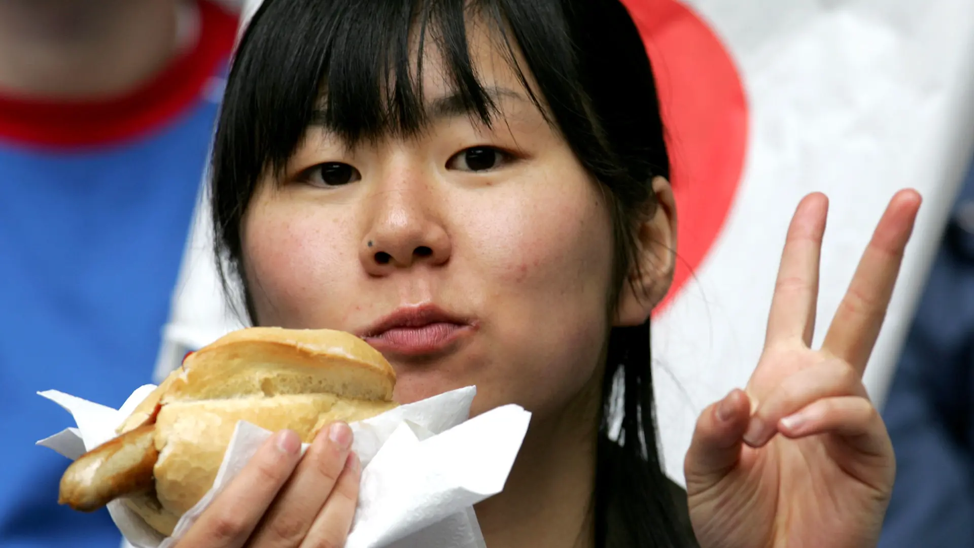 Fußball, Testspiel, Japan - Malta, am Sonntag (04.06.2006) in der LTU-Arena in Düsseldorf. Eine Japanerin isst eine Currywurst und macht das Victory-Zeichen. Foto: Rolf Vennenbernd dpa/lnw +++(c) dpa - Bildfunk+++