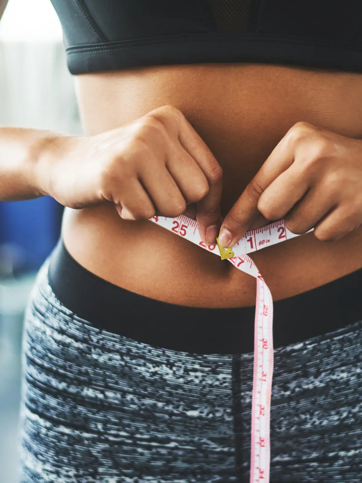 Cropped shot of a fit young woman measuring her waist in a gym