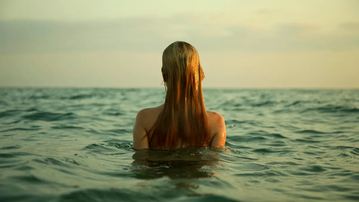 The girl swiming in sea waves. An art photo. A beautiful landscape.