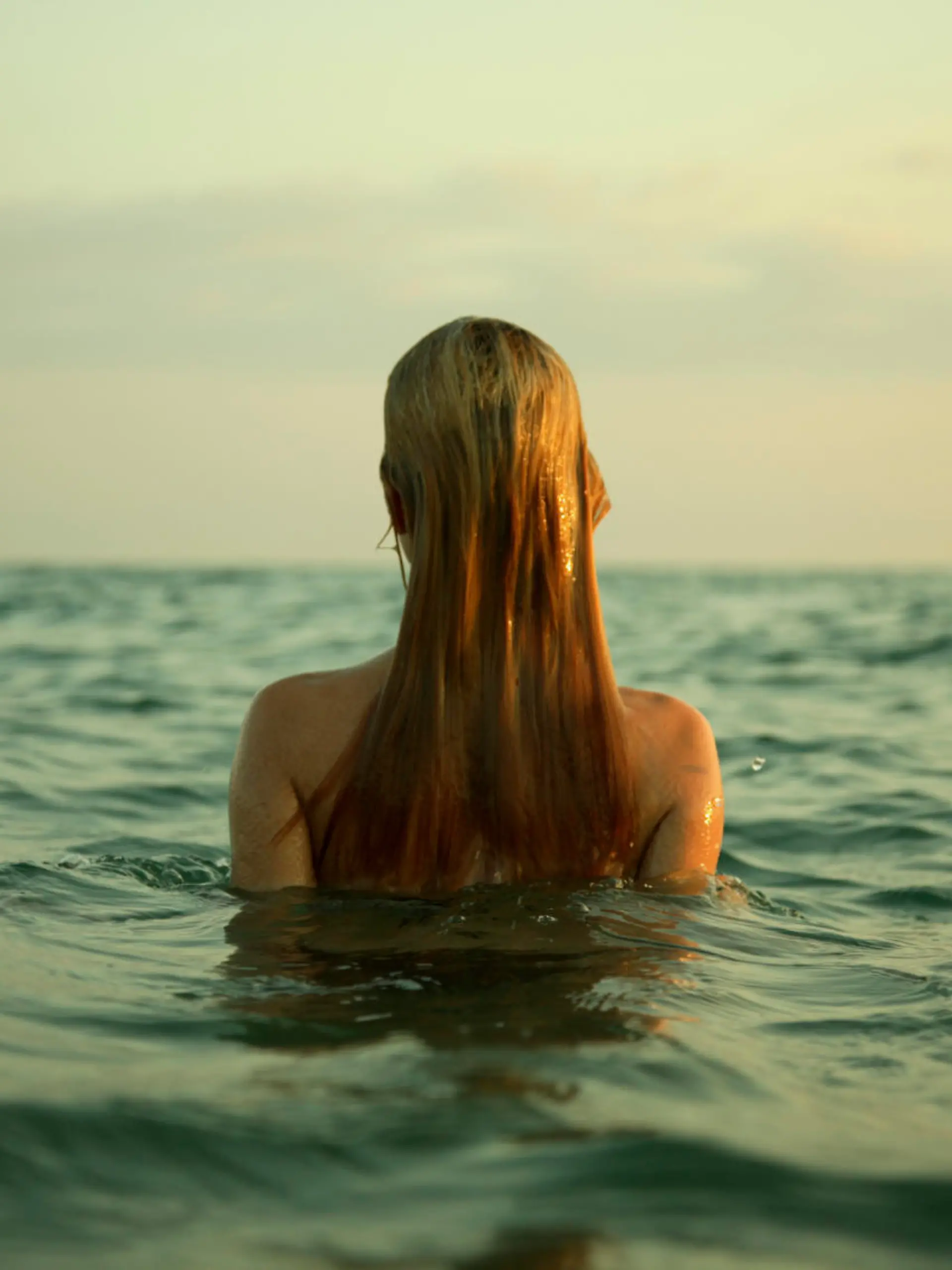 The girl swiming in sea waves. An art photo. A beautiful landscape.