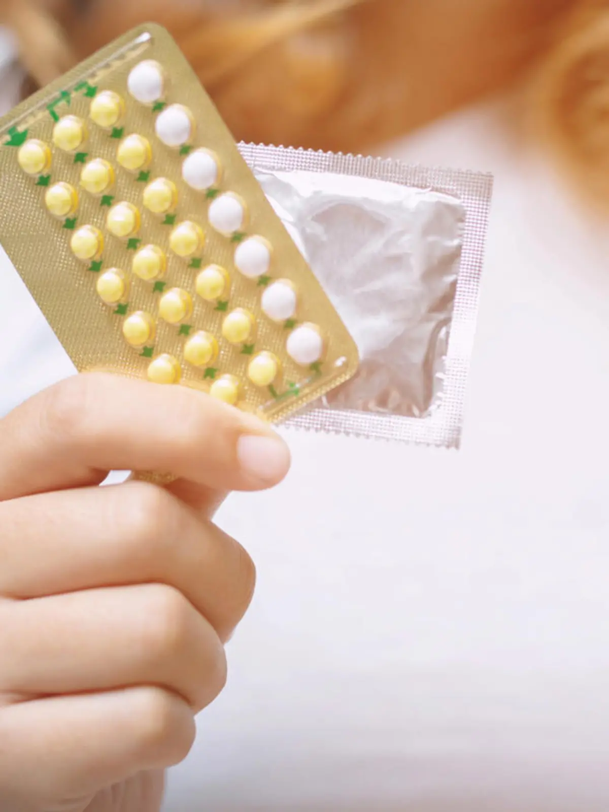 Woman hands give birth control pills and condom in hand. Taking Contraceptive Pill. safe sex concept on the bed Prevent infection and Contraceptives control the birth rate or safe prophylactic.