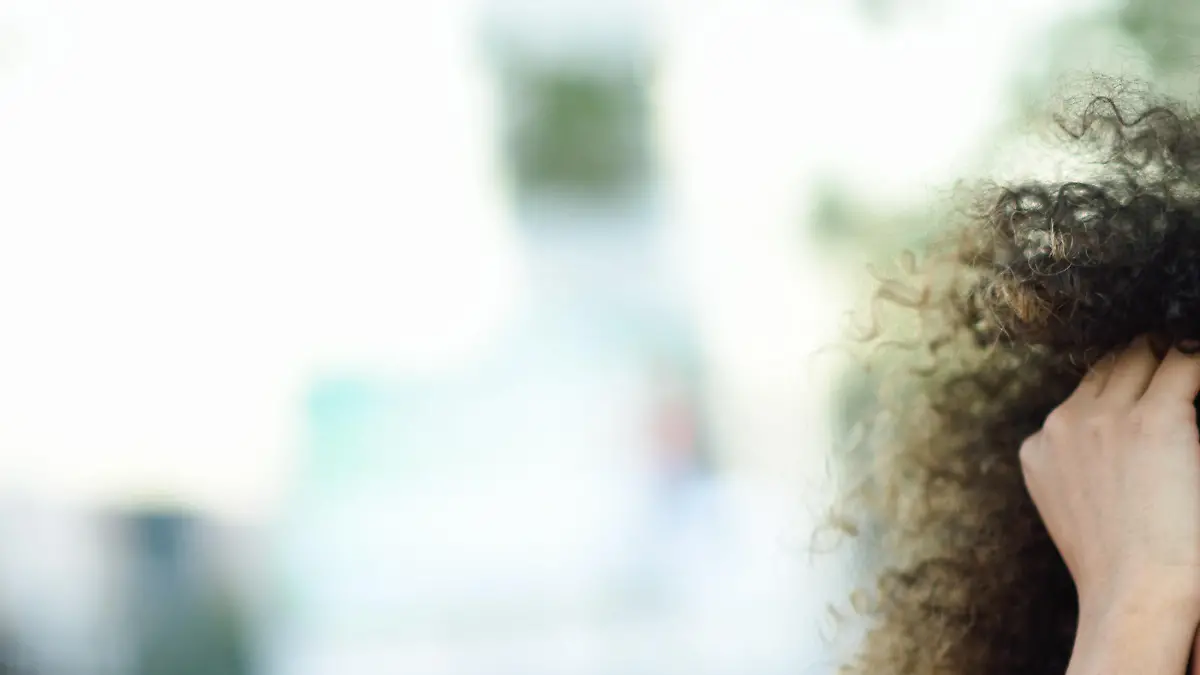 Young black woman with afro hairstyle smiling in urban background. Mixed girl wearing casual clothes.
