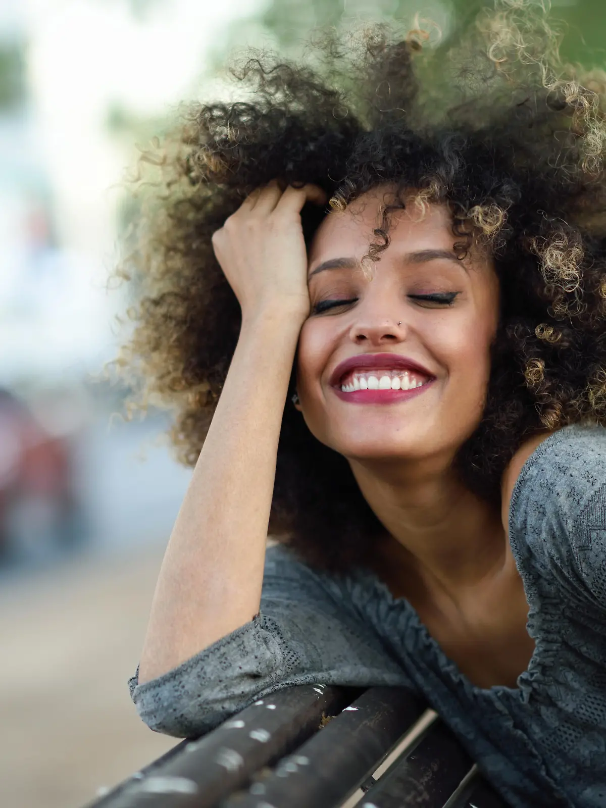 Young black woman with afro hairstyle smiling in urban background. Mixed girl wearing casual clothes.