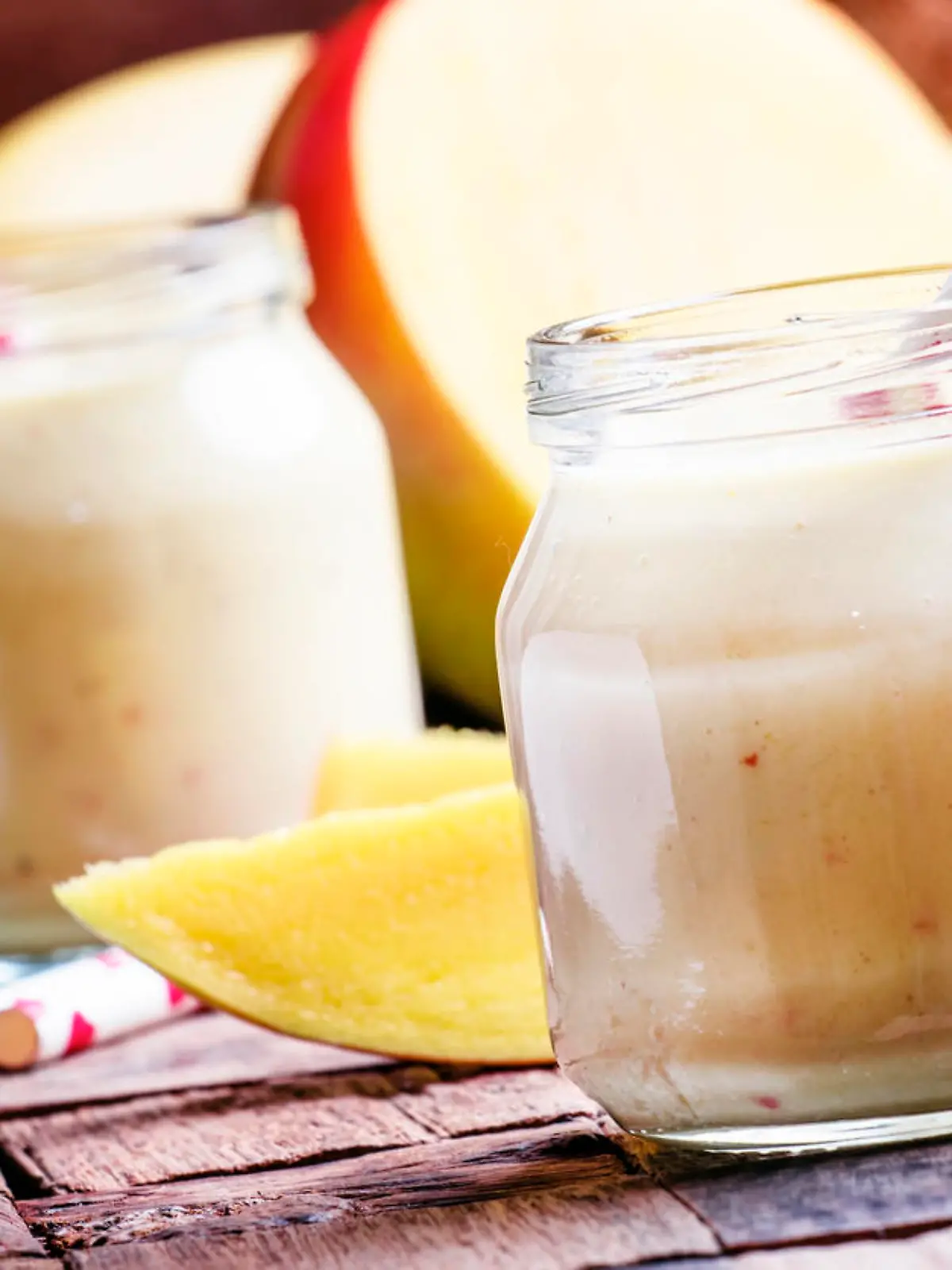 Banana mango smoothie with coconut in a glass jar, vintage wooden background, selective focus