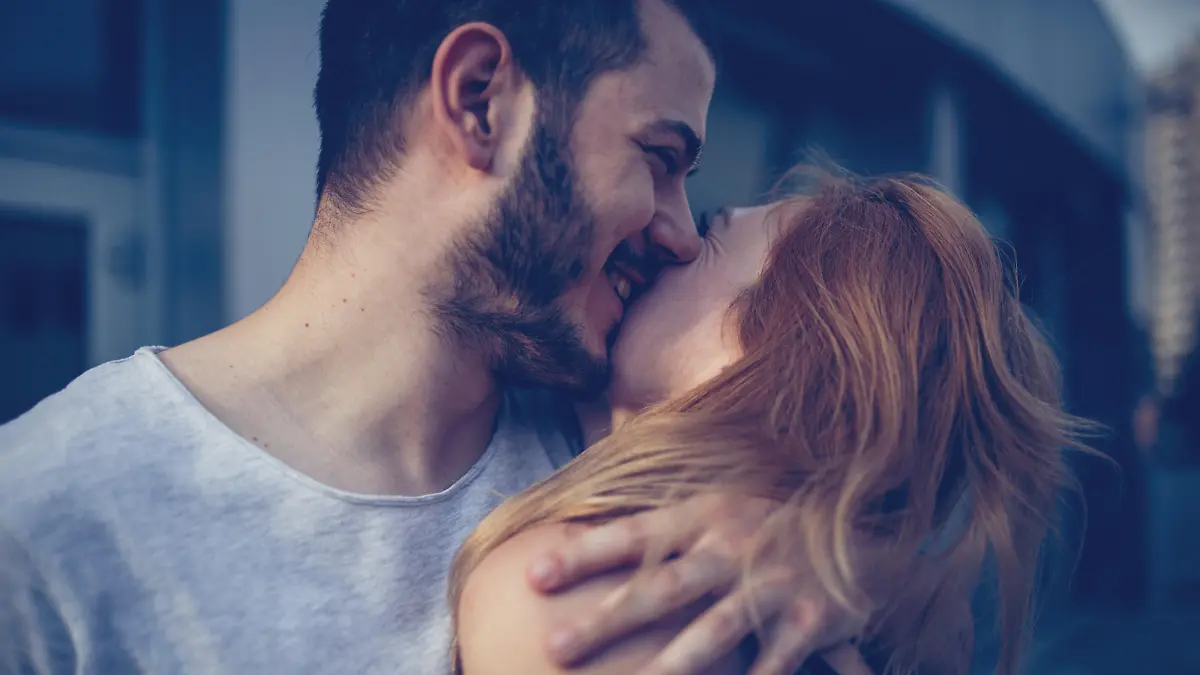 Man and woman enjoying a sunny day in the city, they are hugging and kissing