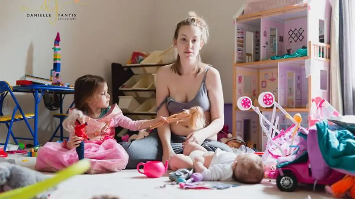 Erschöpfte Mutter sitzt auf dem Boden mit ihren Kindern. Sie leidet an postpartale Depression.