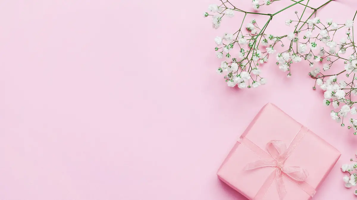 Gift or present box and flower on pink table from above. Pastel color. Greeting card. Flat lay style.