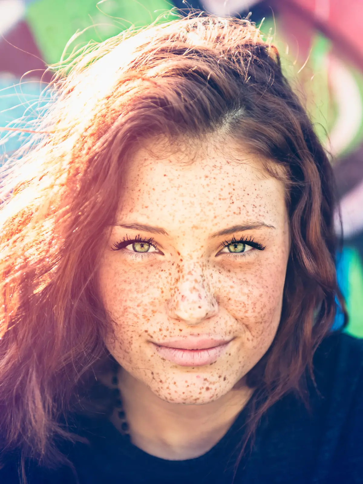Portrait of young woman with freckles, graffitti on background
