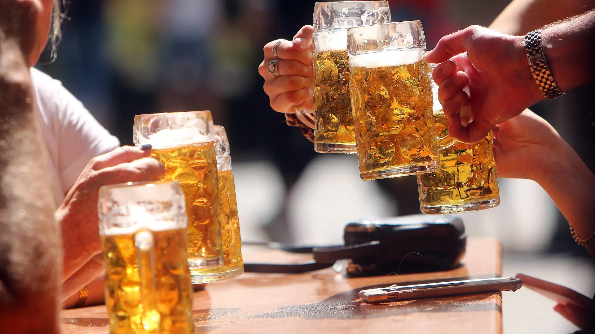 Gemeinsames Zuprosten mit Maßkrüge n Bier im Biergarten am Viktualienmarkt in München, Bayern, Deutschland *** Joint frosting with beer mugs in the beer garden at Viktualienmarkt in Munich, Bavaria, Germany