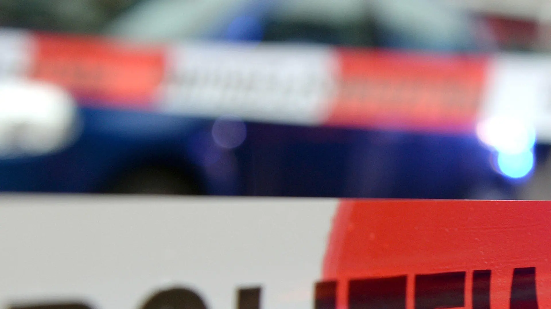 ARCHIV - ILLUSTRATION - Ein Flatterband mit der Aufschrift «Polizeiabsperrung» ist am 05.11.2014 in Freiburg (Baden-Württemberg) an einem Einsatzort vor einem Feuerwehrfahrzeug mit Blaulicht zu sehen. Mit einem Samuraischwert soll ein 38-Jähriger seinen Cousin getötet haben. Auf einer Familienfeier bei Bergisch Gladbach in Nordrhein-Westfalen seien die beiden Männer in Streit geraten. (Illustration zu dpa "Cousin bei Familienfeier mit Samuraischwert getötet" vom 12.08.2017) Foto: Patrick Seeger/dpa +++(c) dpa - Bildfunk+++