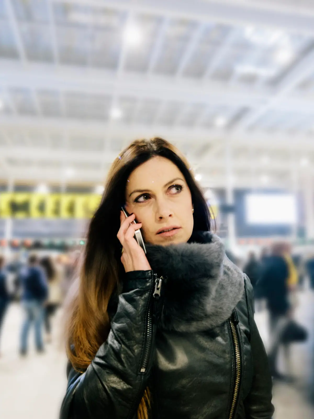 A British woman standing in railway station, waiting for a train, using her mobile telephone.