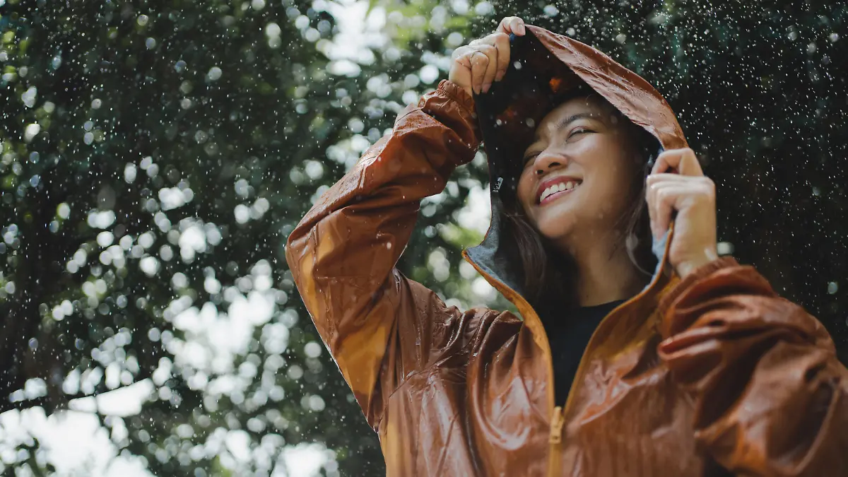Asian woman is outdoors while it's raining. She felt refreshed.