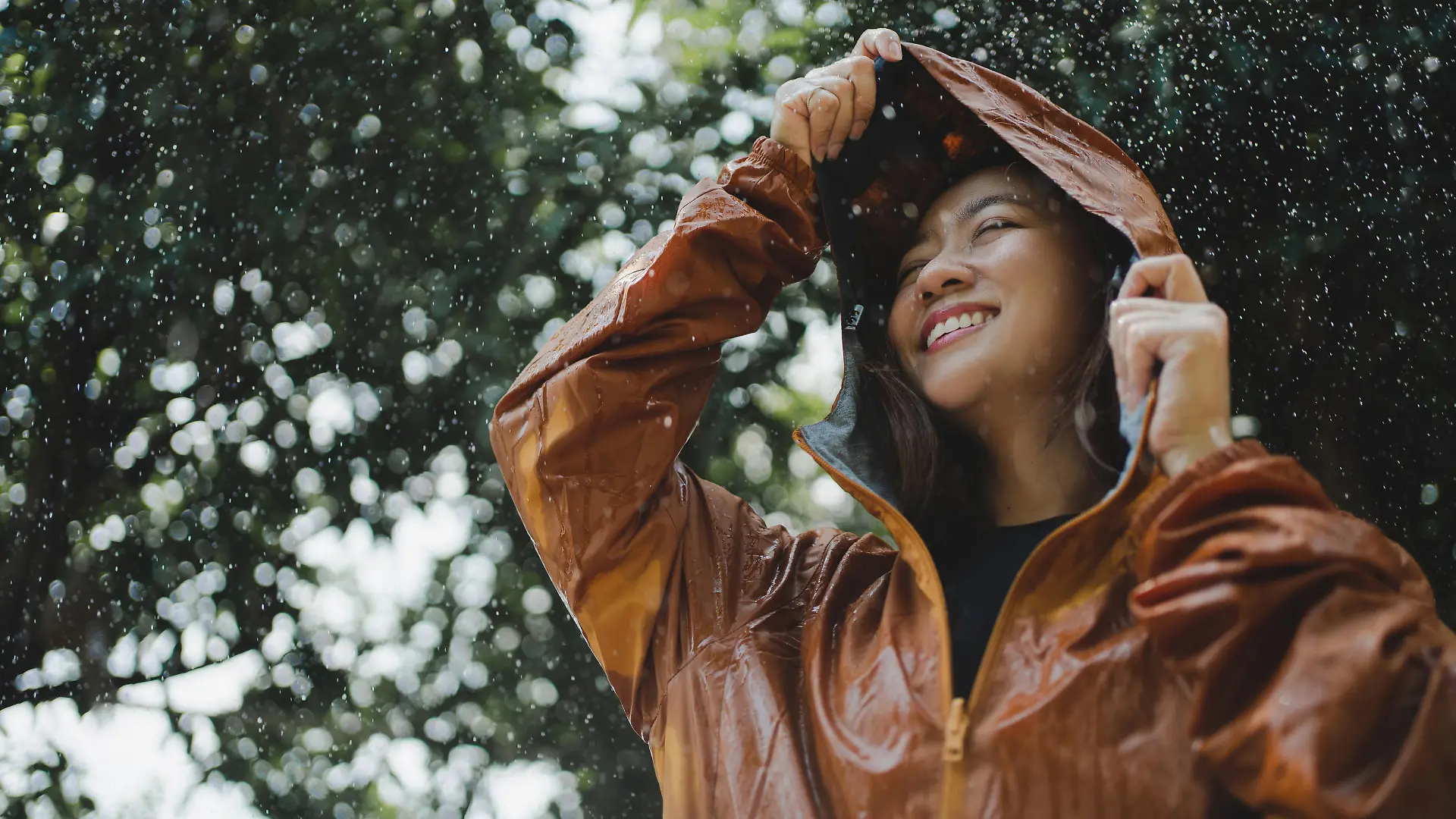 Asian woman is outdoors while it's raining. She felt refreshed.