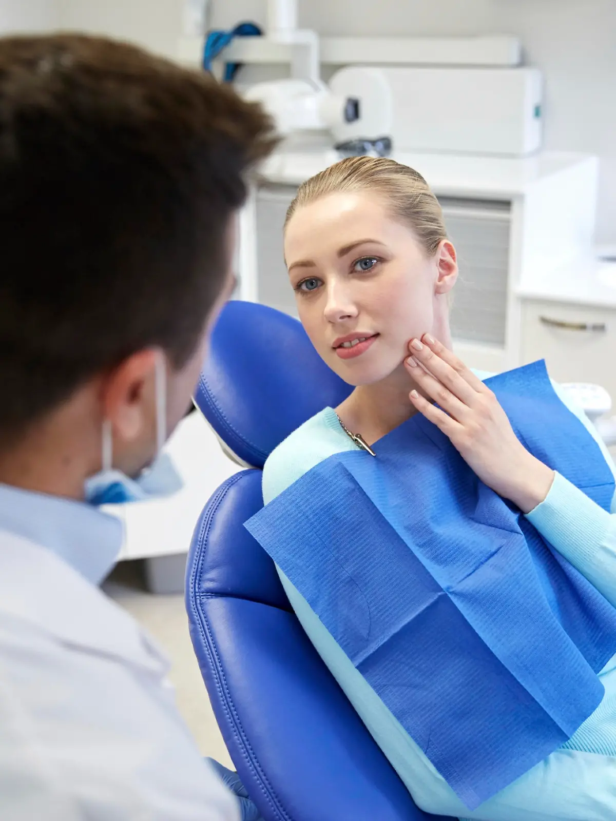 people, medicine, stomatology and health care concept - woman patient talking to male dentist and complain of toothache at dental clinic office