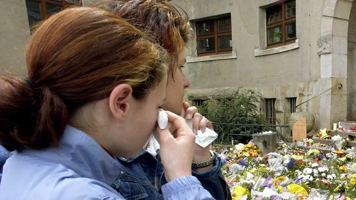 ARCHIV - Zwei junge Mädchen weinen am 28.04.2002 vor den mit Blumen und Kerzen übersäten Treppenstufen am Eingangsportal des Gutenberg-Gymnasiums in Erfurt. Ein Jahrzehnt ist es her, dass ein Ex-Schüler am Gutenberg-Gymnasium 16 Menschen erschoss und sich selbst tötete. Es war der erste Amoklauf dieser Dimension an einer deutschen Schule. Am 26. April 2012 jährt sich das Massaker zum zehnten Mal. Foto: Stephanie Pilick dpa/lth (zu Themenpaket «Gedenken am Gutenberg-Gymnasium» zum 26. April 2012)  +++(c) dpa - Bildfunk+++