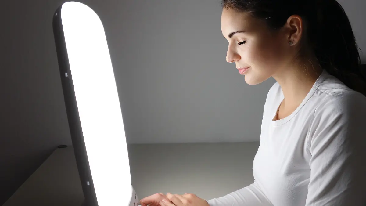 Junge Frau sitzt vor einer Tageslichtlampe