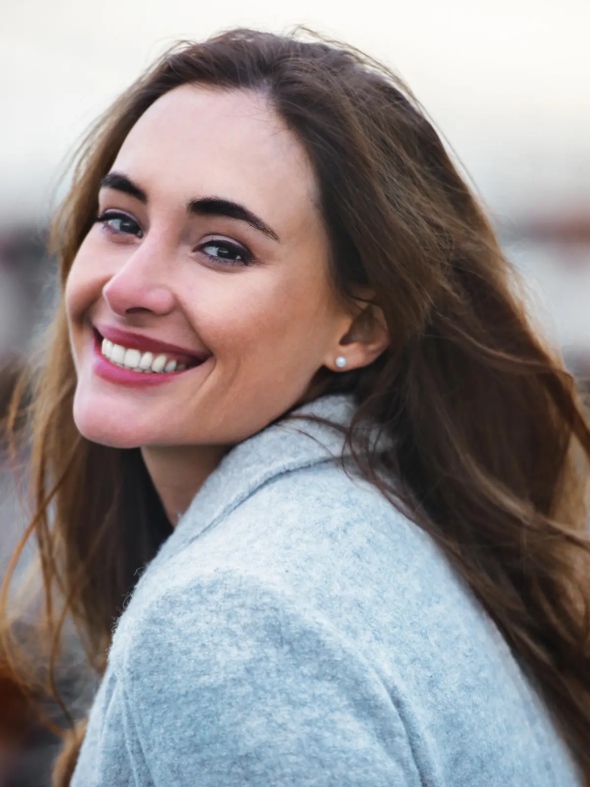 Close-up portrait of beautiful caucasian woman with charming smile walking outdoors