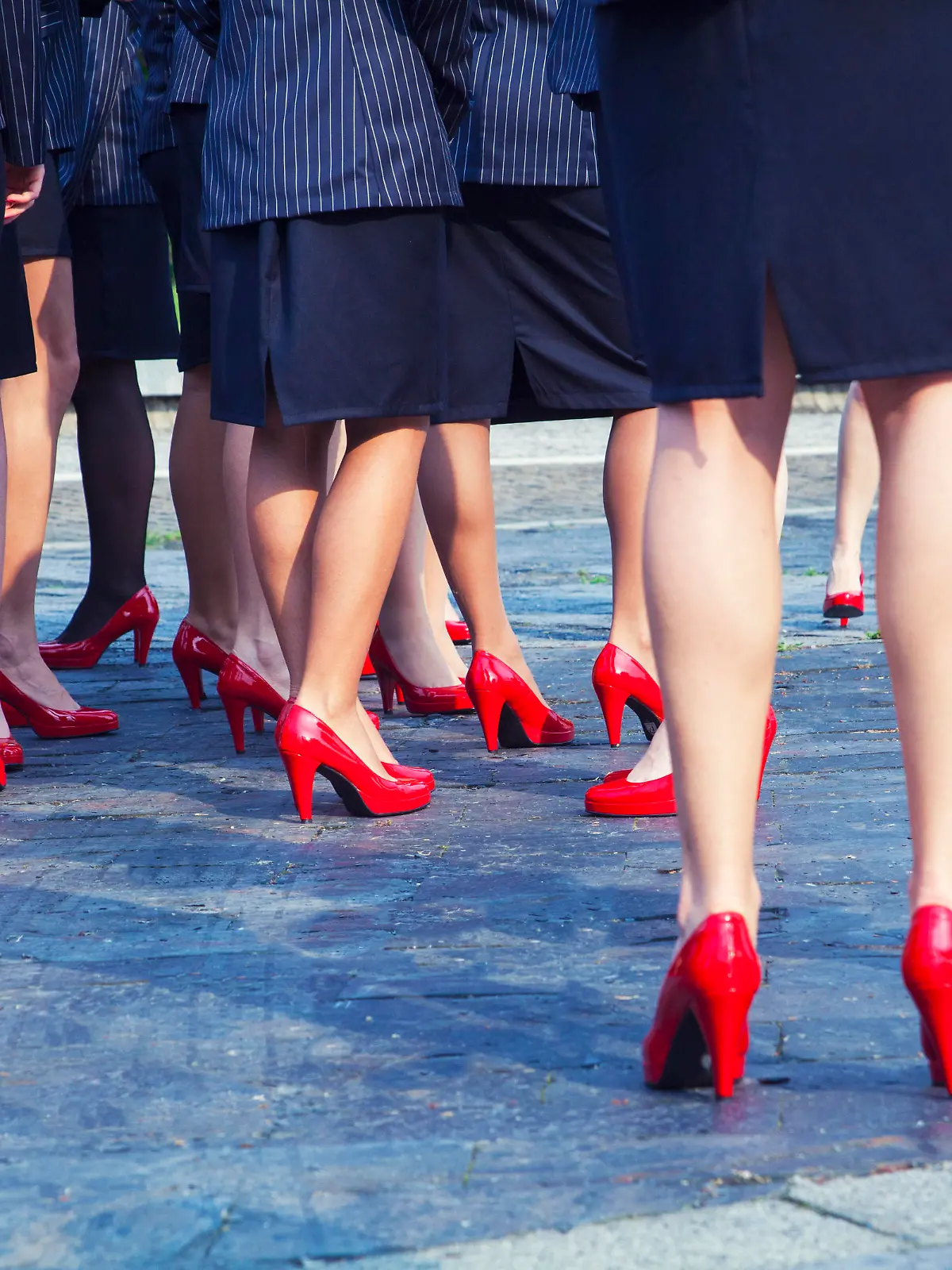 Lower body view of a business women outside in the morning before work wearing red heels.