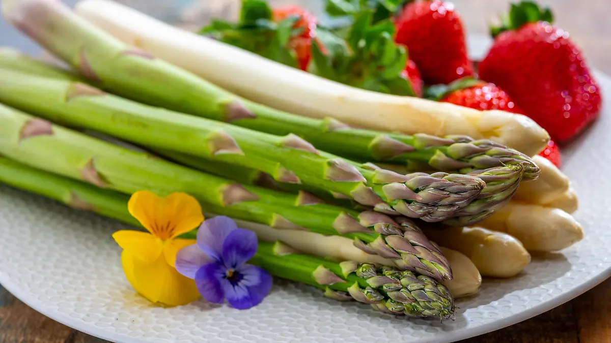 Springtime in Netherlands, high quality Dutch white asparagus, washed and peeled on board with fresh ripe strawberry
