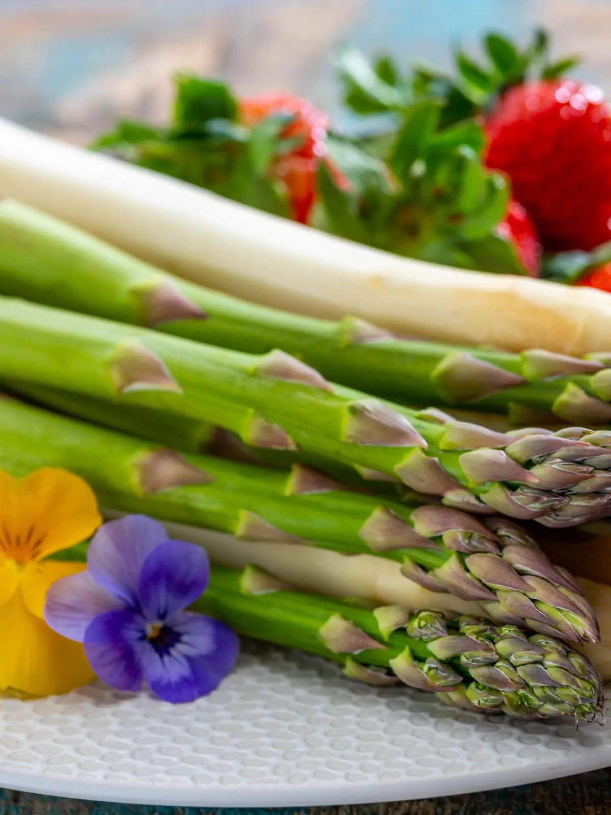 Springtime in Netherlands, high quality Dutch white asparagus, washed and peeled on board with fresh ripe strawberry