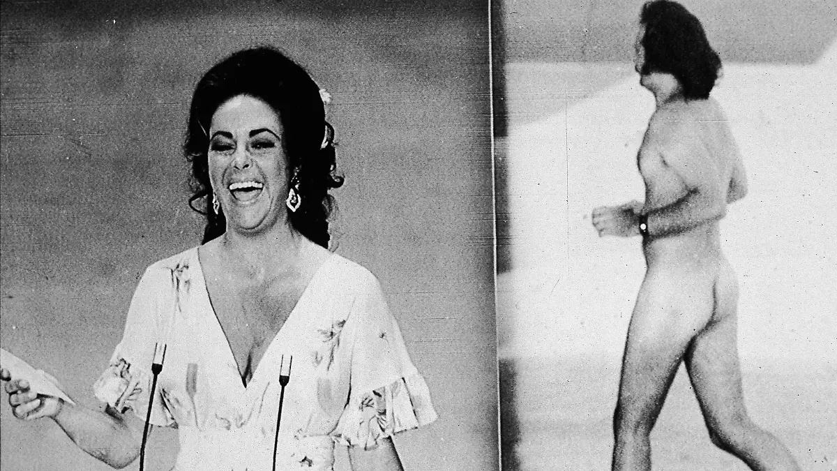British-born actress Elizabeth Taylor laughs as she remarks that she was upstaged by streaker Robert Opal before presenting the Oscar for Best Picture at the 46th Annual Academy Awards ceremony, Los Angeles, California, April 2, 1974. At right, Opal darts across the stage naked just as David Niven was introducing Taylor. (Photo by Hulton Archive/Getty Images)