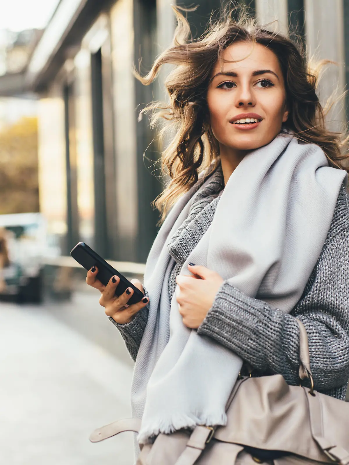 A young woman texting on the phone outdoor in the city.