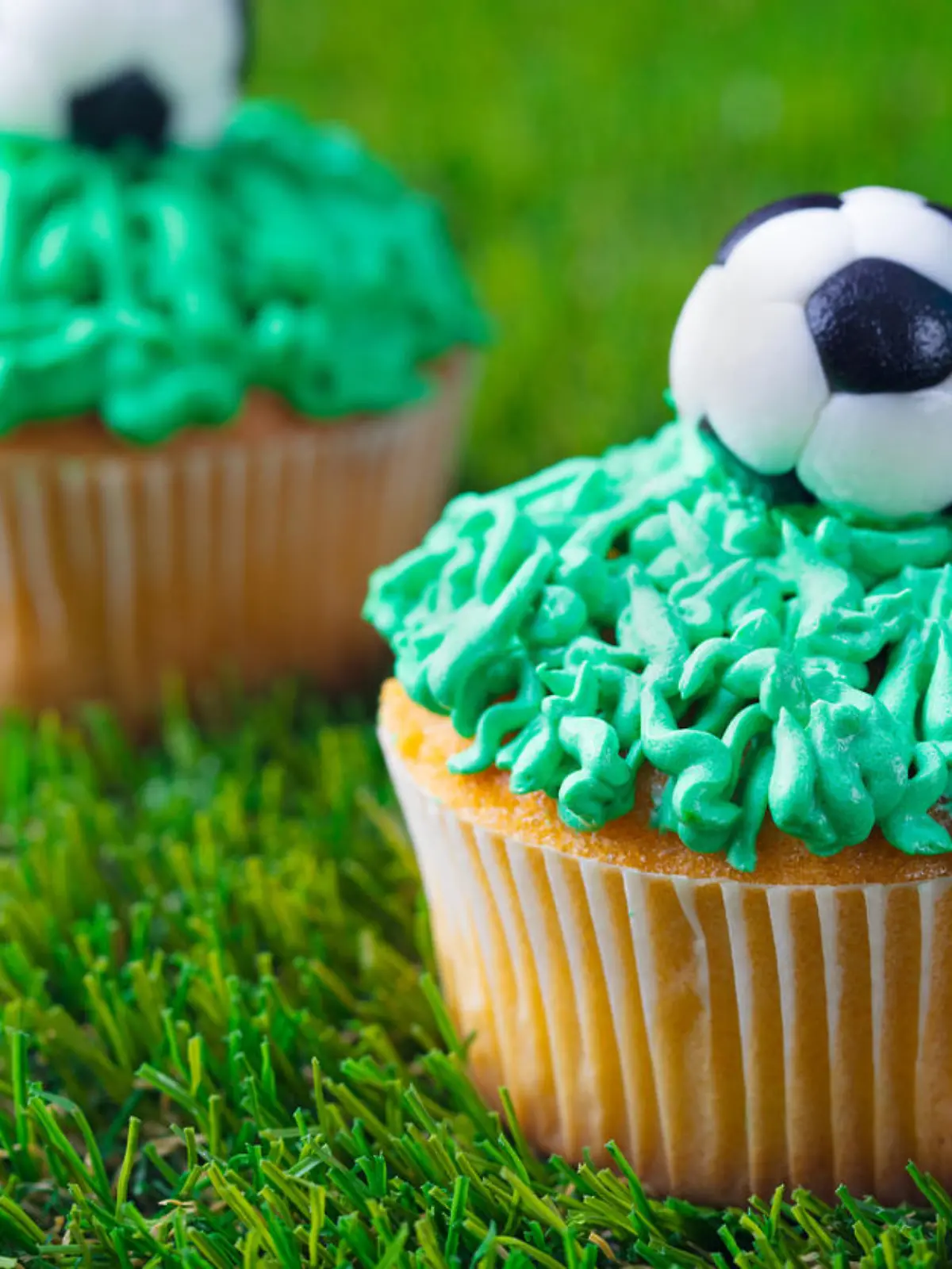 Football party, birthday decorated cupcake on green grass background. Close up