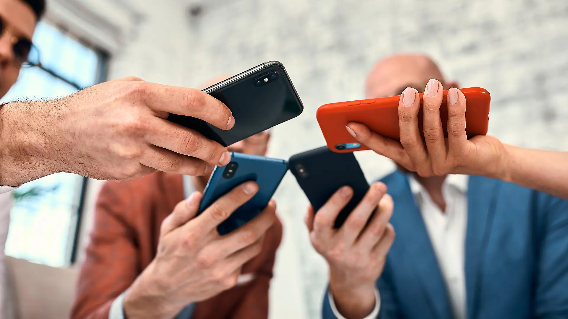 Male and female diverse hands holding cell phones, multiracial business people using smartphones applications software, users and devices concept, mobile communication.
