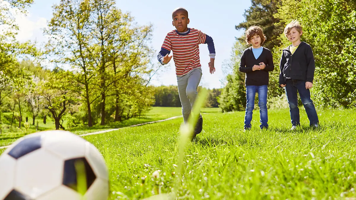 Kinder beim Fußball Training auf einer grünen Wiese im Sonnenschein im Ferienlager || Modellfreigabe vorhanden