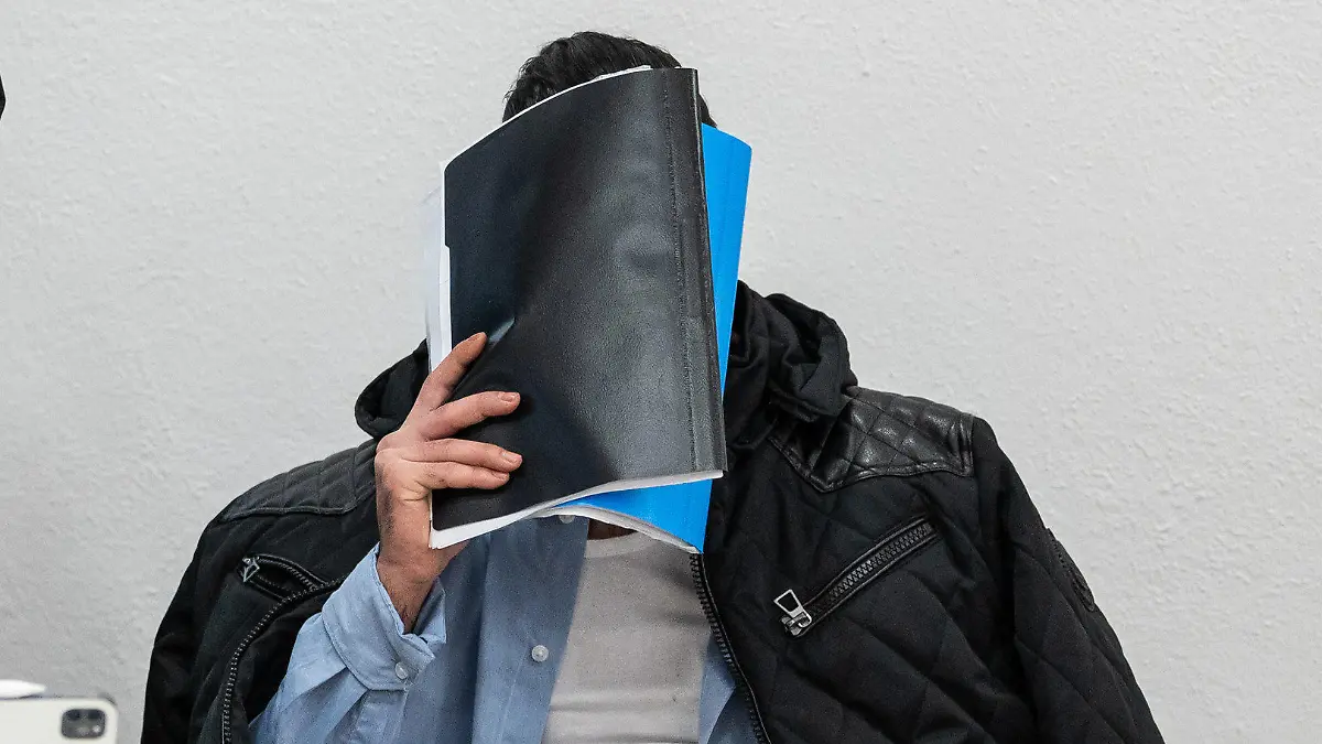 26.01.2023, Baden-Württemberg, Konstanz: Ein Mann, der wegen Vergewaltigung und Freiheitsberaubung an seiner Schwester angeklagt ist, verdeckt vor Beginn des Prozesses sein Gesicht. Verteidiger Sandro Durante (l), steht vor Prozessbeginn im Gerichtssaal neben seinem Mandanten. Der Angeklagten soll seine, zur Tatzeit 18-jährige, Schwester in seinem WG-Zimmer in Konstanz eingesperrt, verletzt und mehrmals vergewaltigt haben. Foto: Silas Stein/dpa - ACHTUNG: Person(en) wurde(n) aus rechtlichen Gründen gepixelt +++ dpa-Bildfunk +++