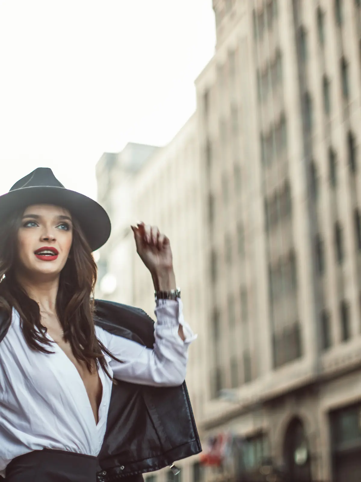 Beautiful young woman in a leater jacket walking down the street in the early spring.