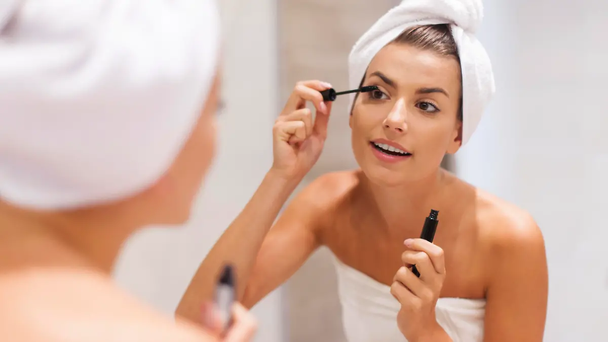 Beautiful woman using mascara in bathroom
