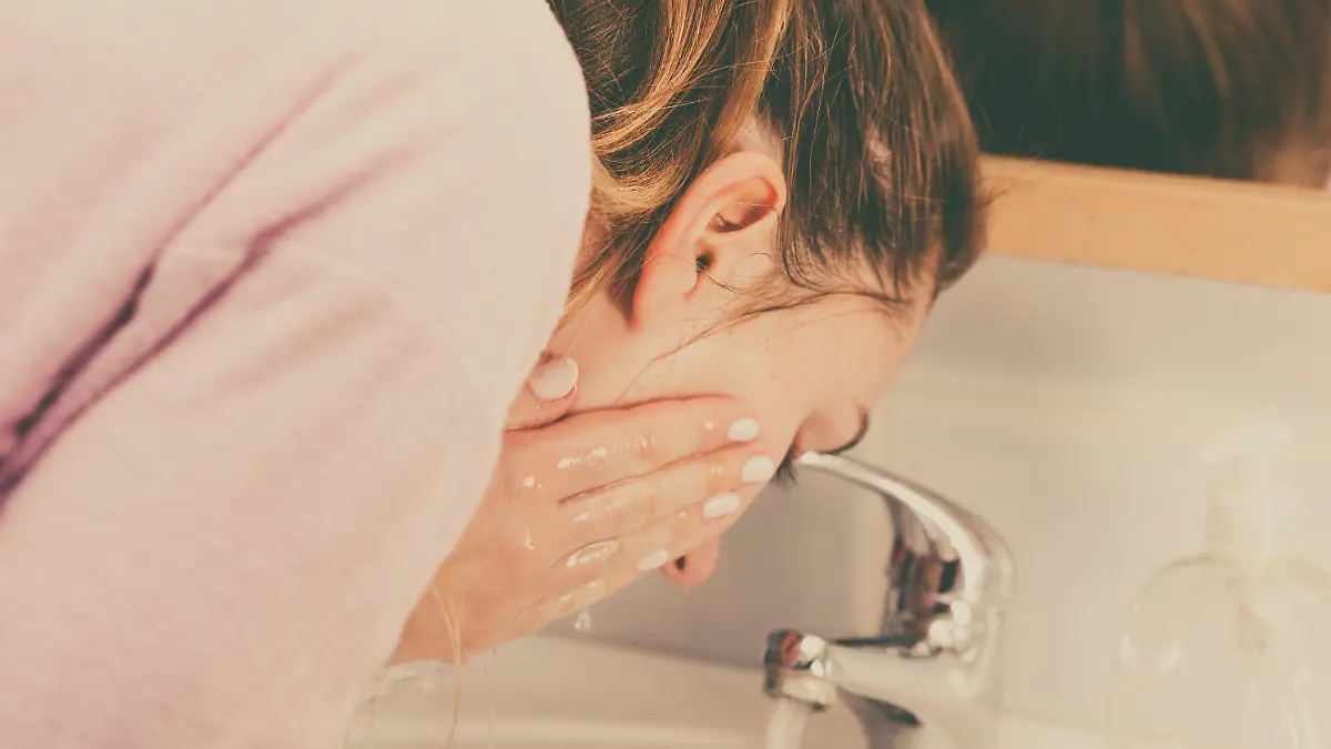 Woman cleaning washing her face with clean water in bathroom. Girl taking care of her complexion. Morning hygiene. Skincare treatment
