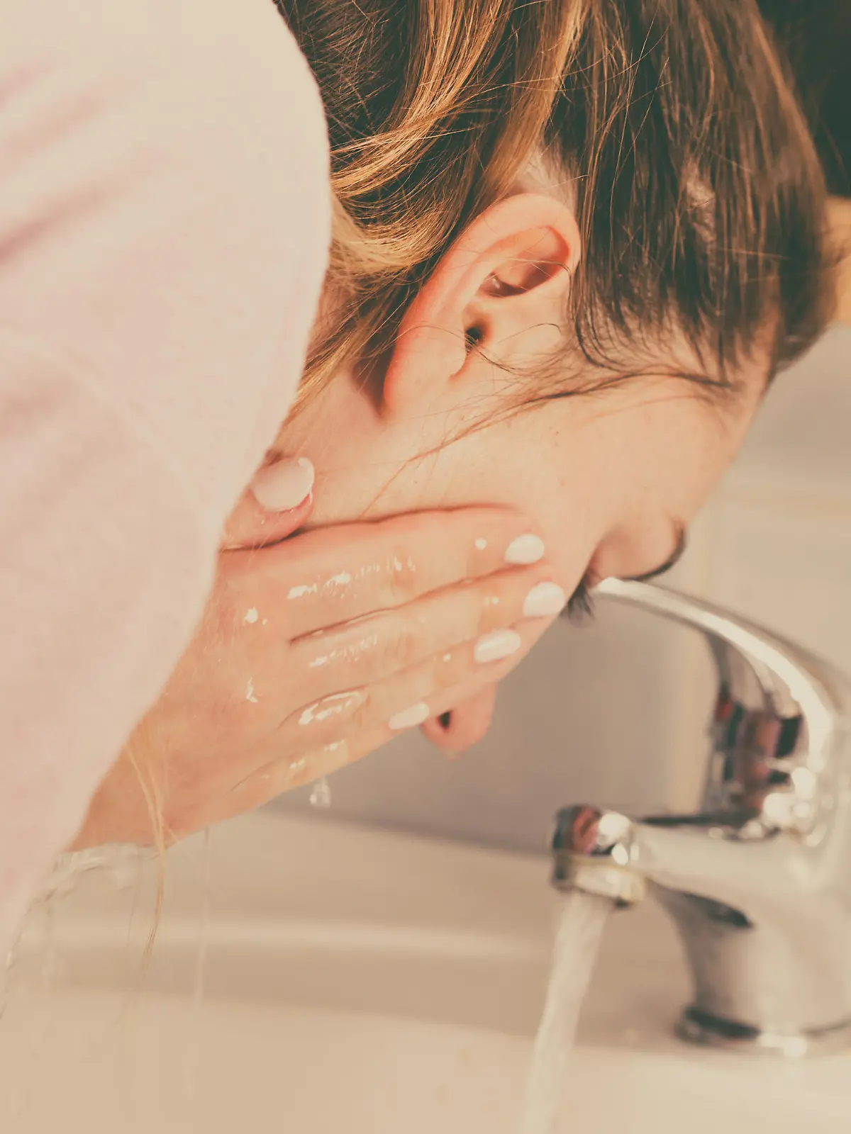 Woman cleaning washing her face with clean water in bathroom. Girl taking care of her complexion. Morning hygiene. Skincare treatment
