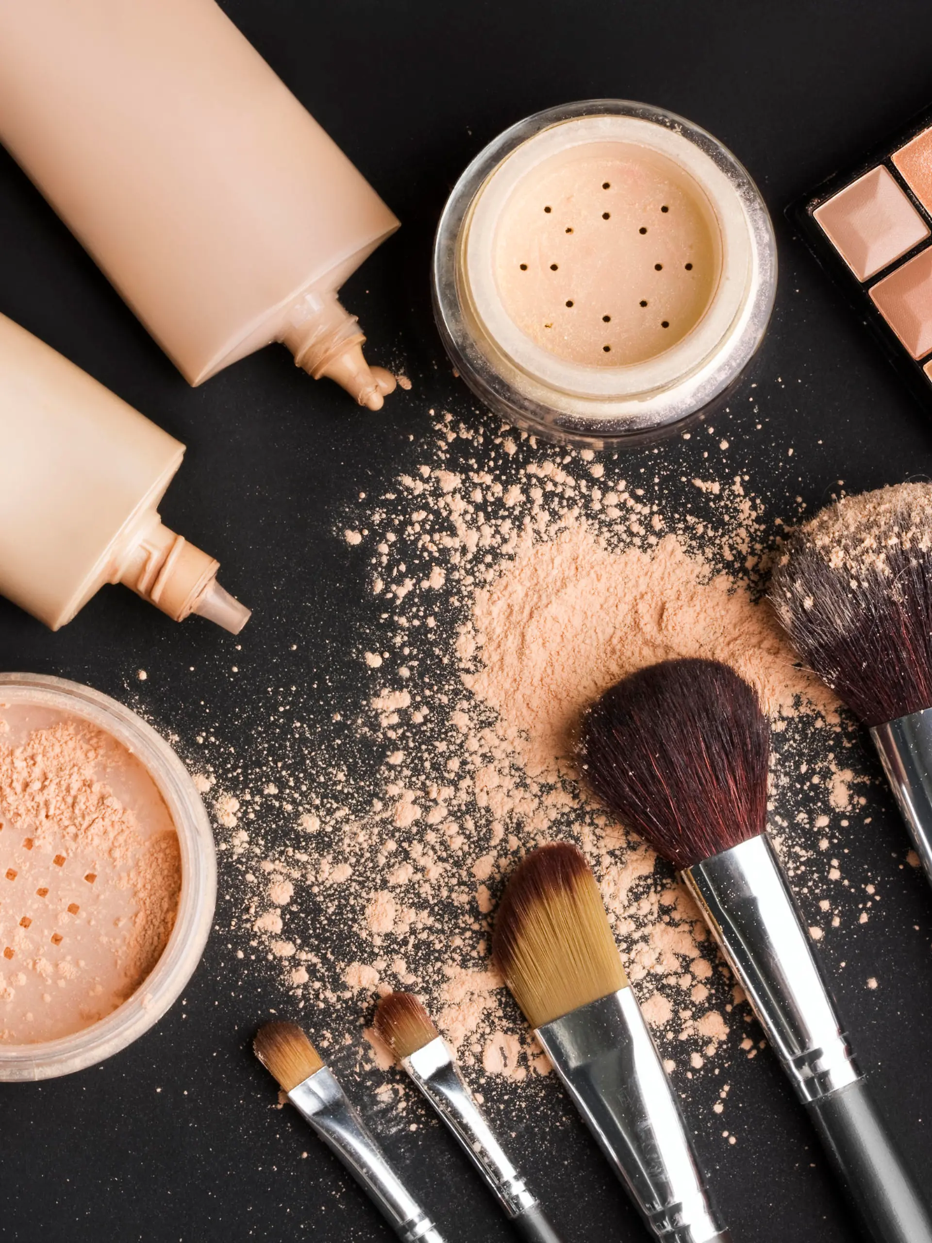 brushes, powder, makeup foundation on black