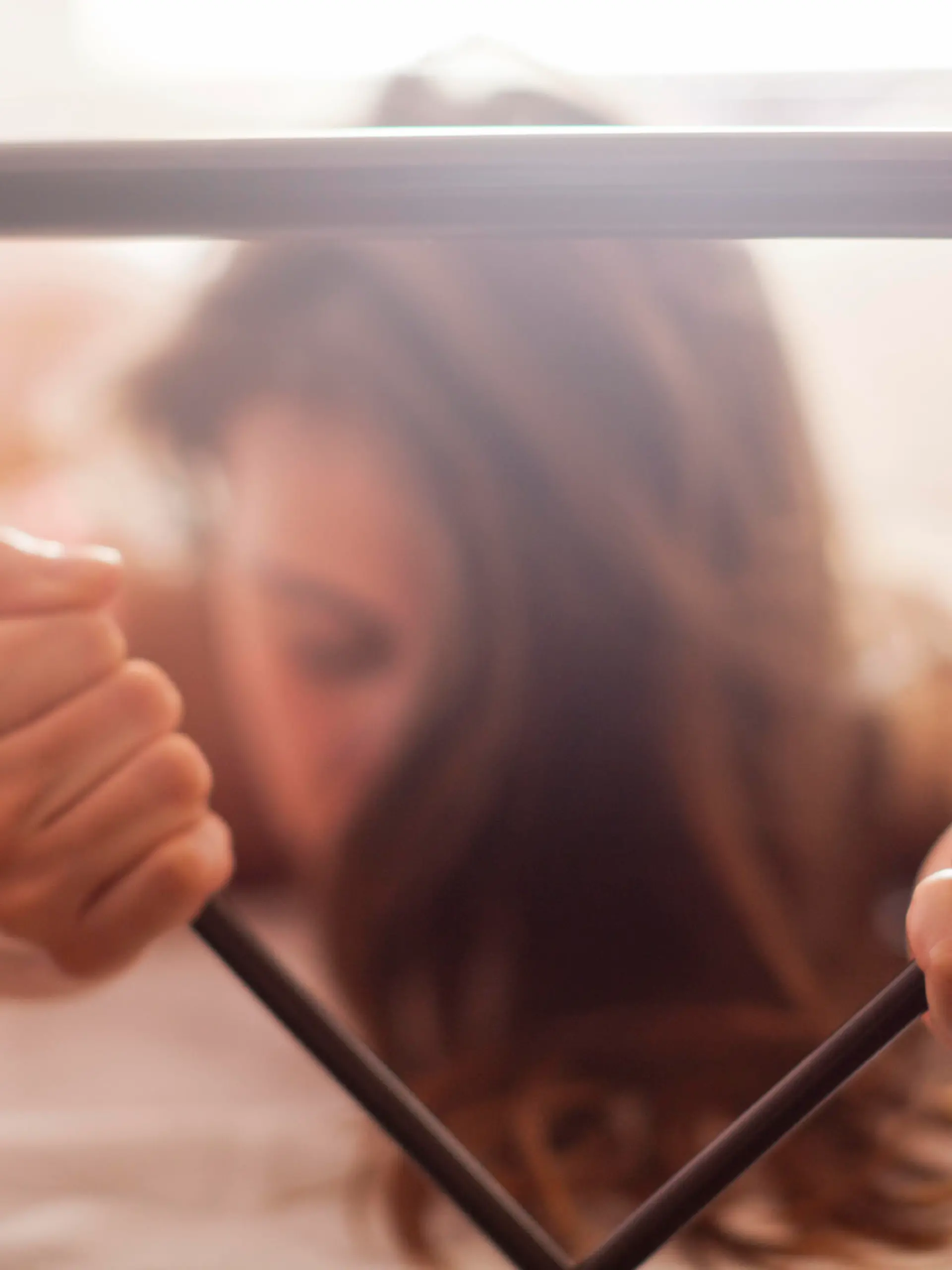 Sexy woman lying naked in bed in the bedroom. She is enjoying in sexual games and during orgasm she squeezes the rod on the bed with great passion. Very shallow depth of field with focus on her left hand