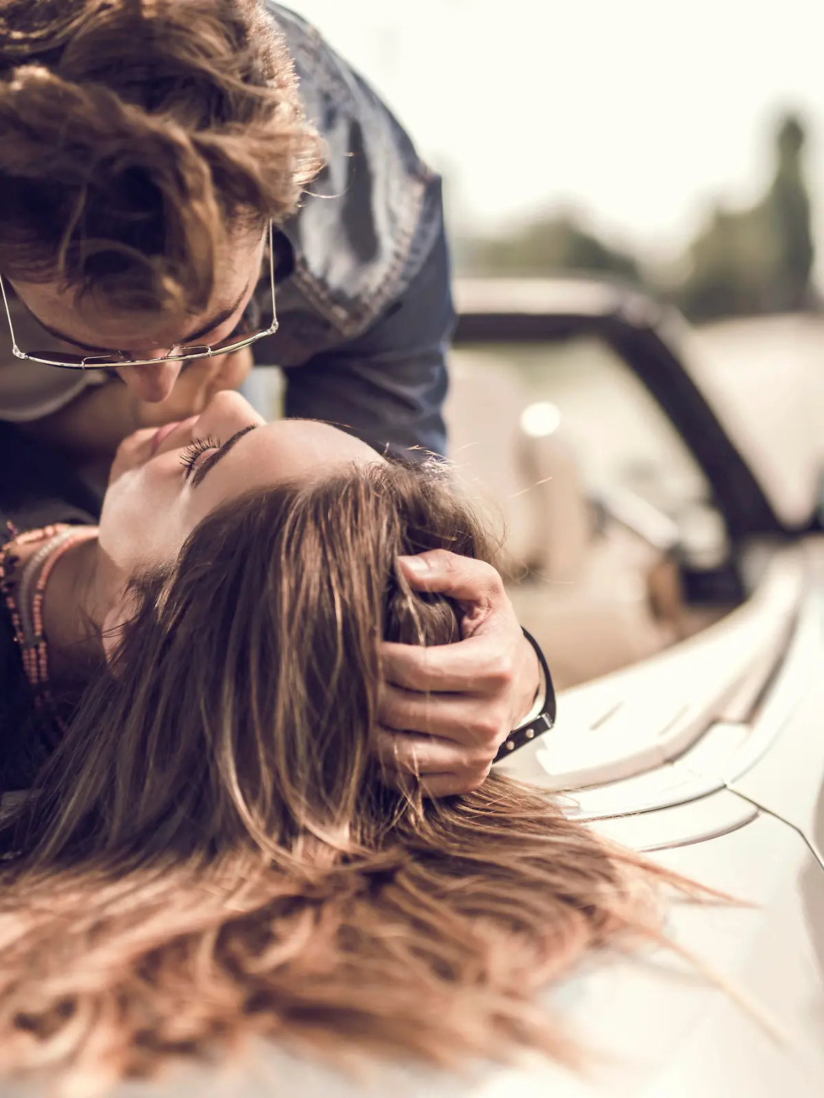 Young loving couple having a desire toward each other while lying on cabriolet.