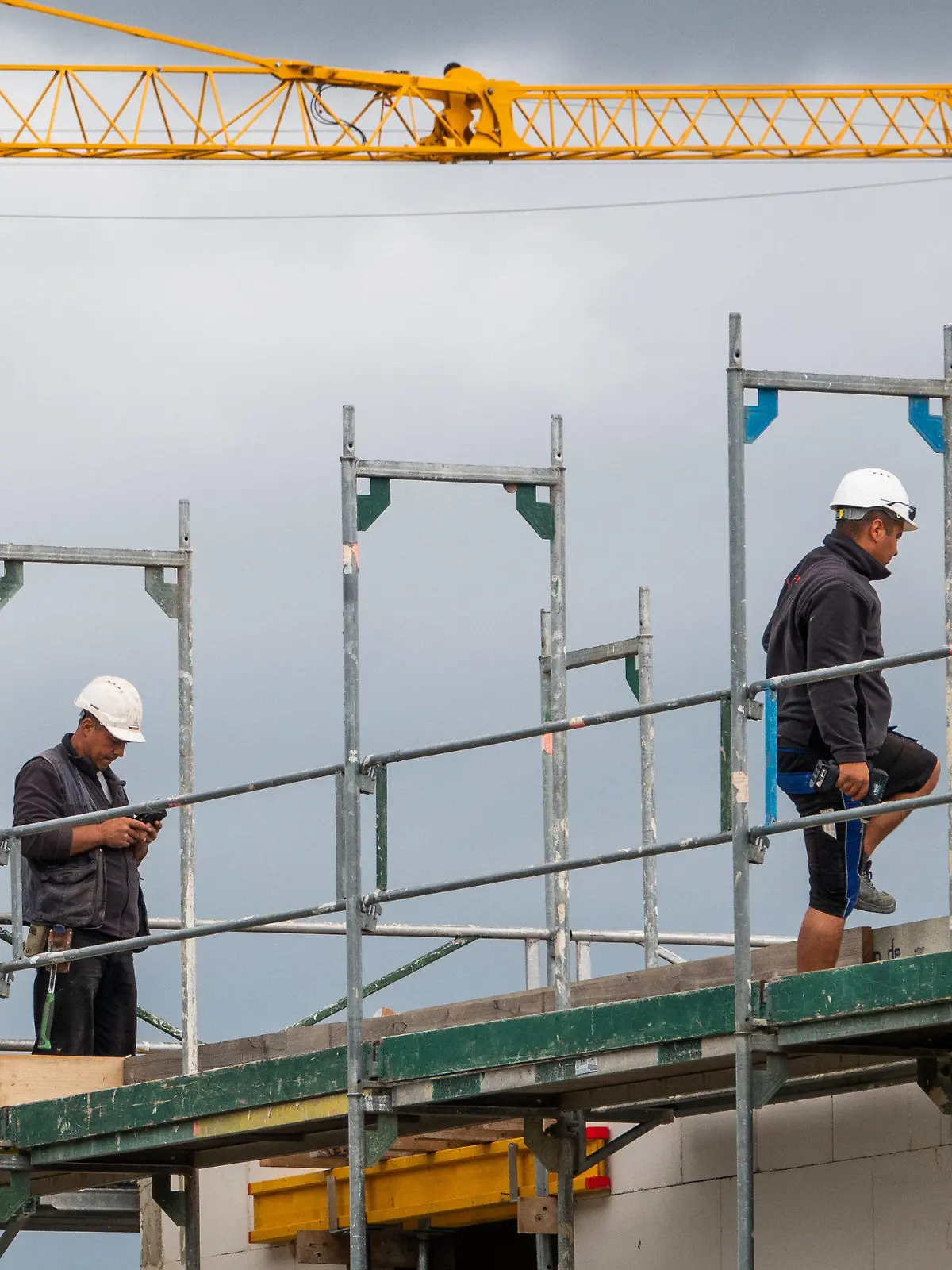 08.07.2019, Niedersachsen, Hannover: Zwei Bauarbeiter gehen auf einer Baustelle auf einem Hausdach auf dem Gerüst. Bauminister Lies (SPD) hat am Montag (08.07.2019) die Ergebnisse des Wohnungsmarktberichts 2018/19 für Niedersachsen vorgestellt. Foto: Cindy Riechau/dpa +++ dpa-Bildfunk +++