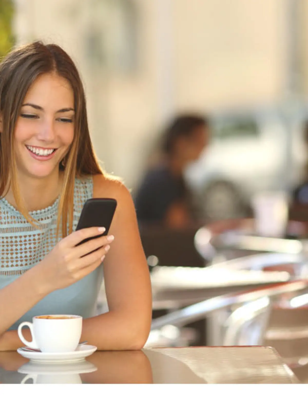 Girl texting on the smart phone in a restaurant terrace with an unfocused background