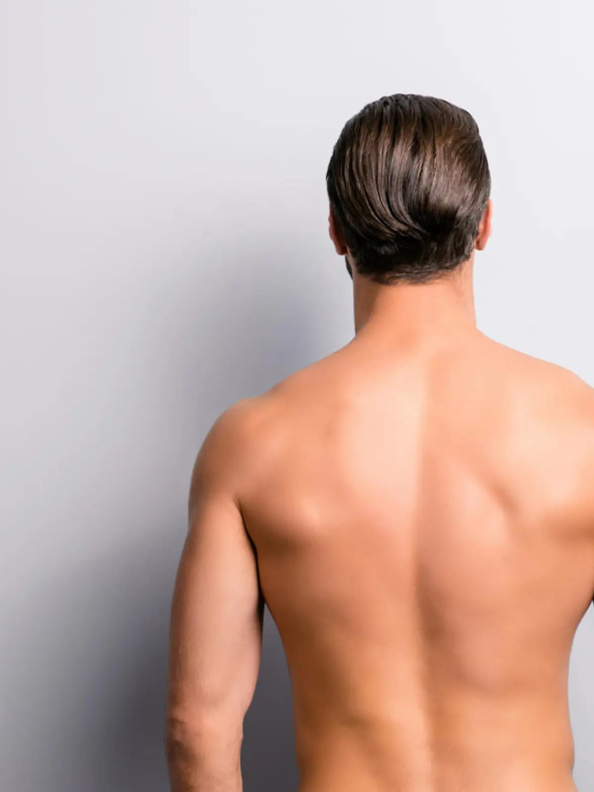 Rear back behind view photo of strong muscular handsome attractive stunning confident ideal perfect sportsman isolated on gray background copyspace