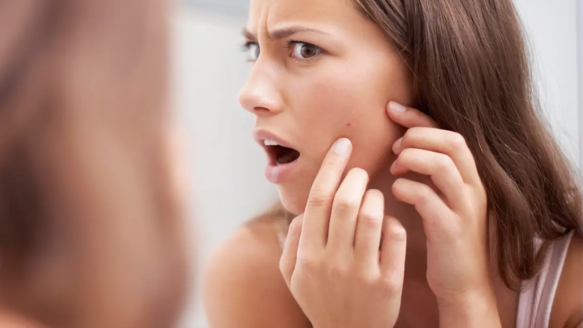 A young woman looking shocked as she examines her skin