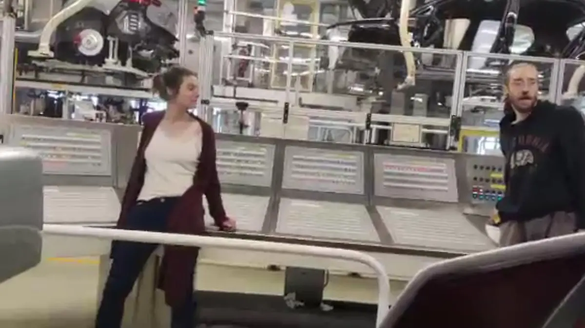 Zwei Menschen in einer Fabrik für Autos.