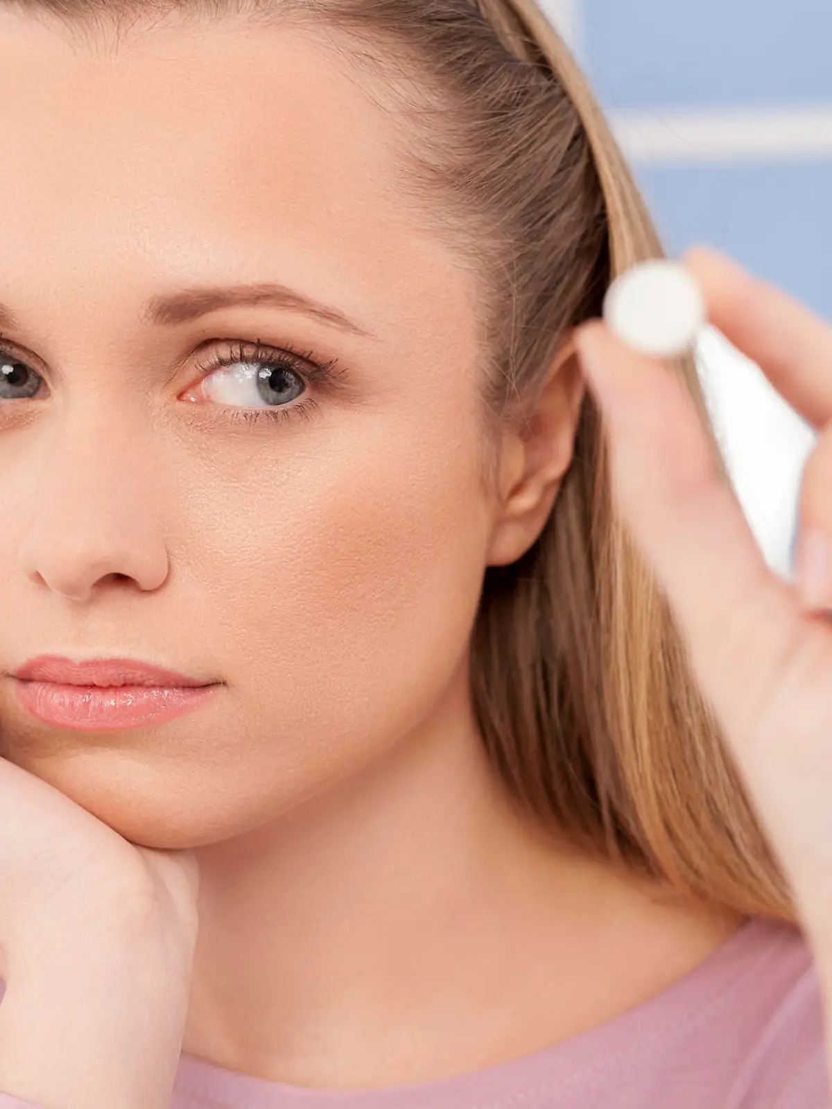 Depressed young woman holding a pill and looking at it