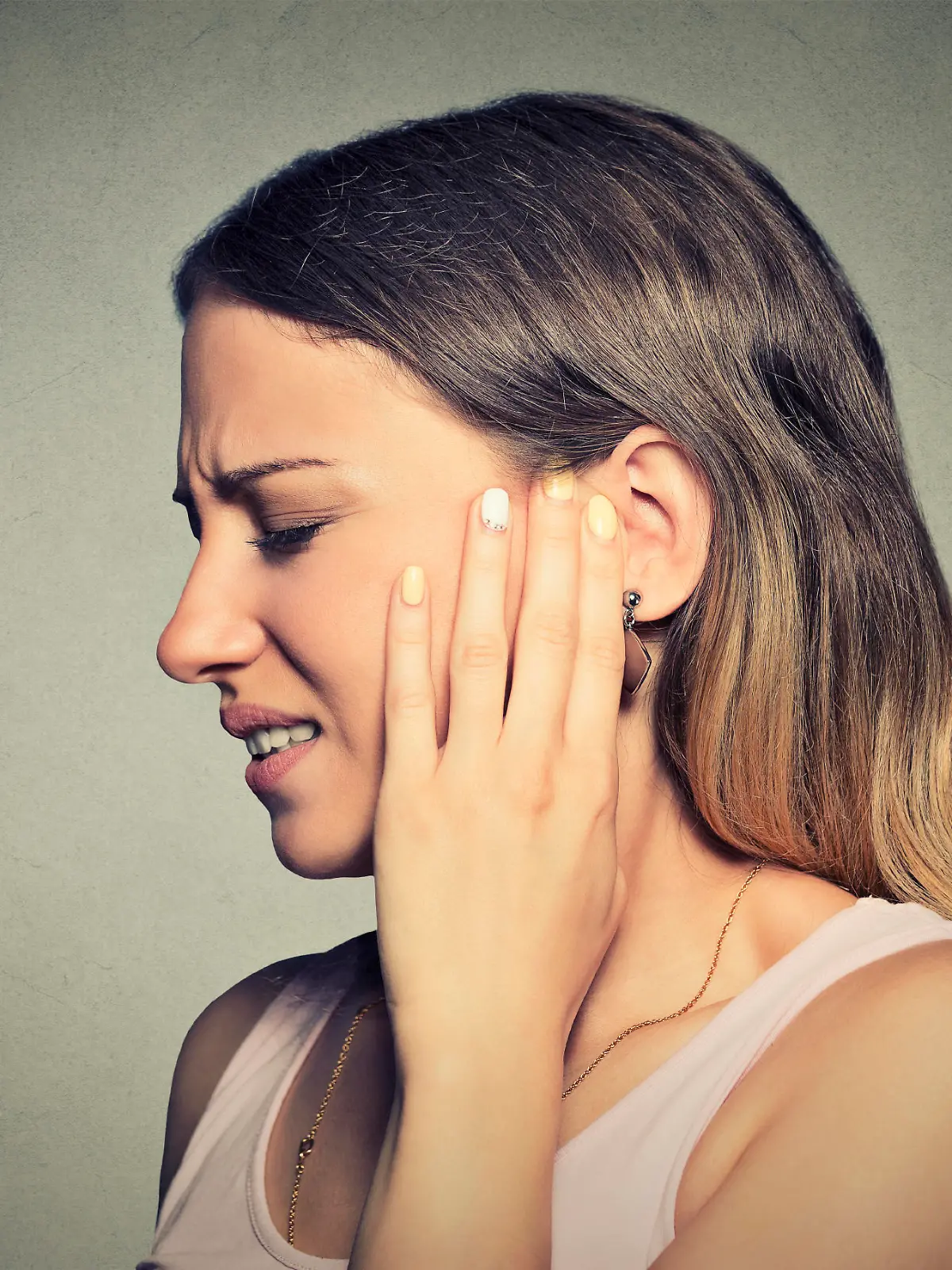 Tinnitus. Closeup side profile sick young woman having ear pain touching her painful head isolated on blue background