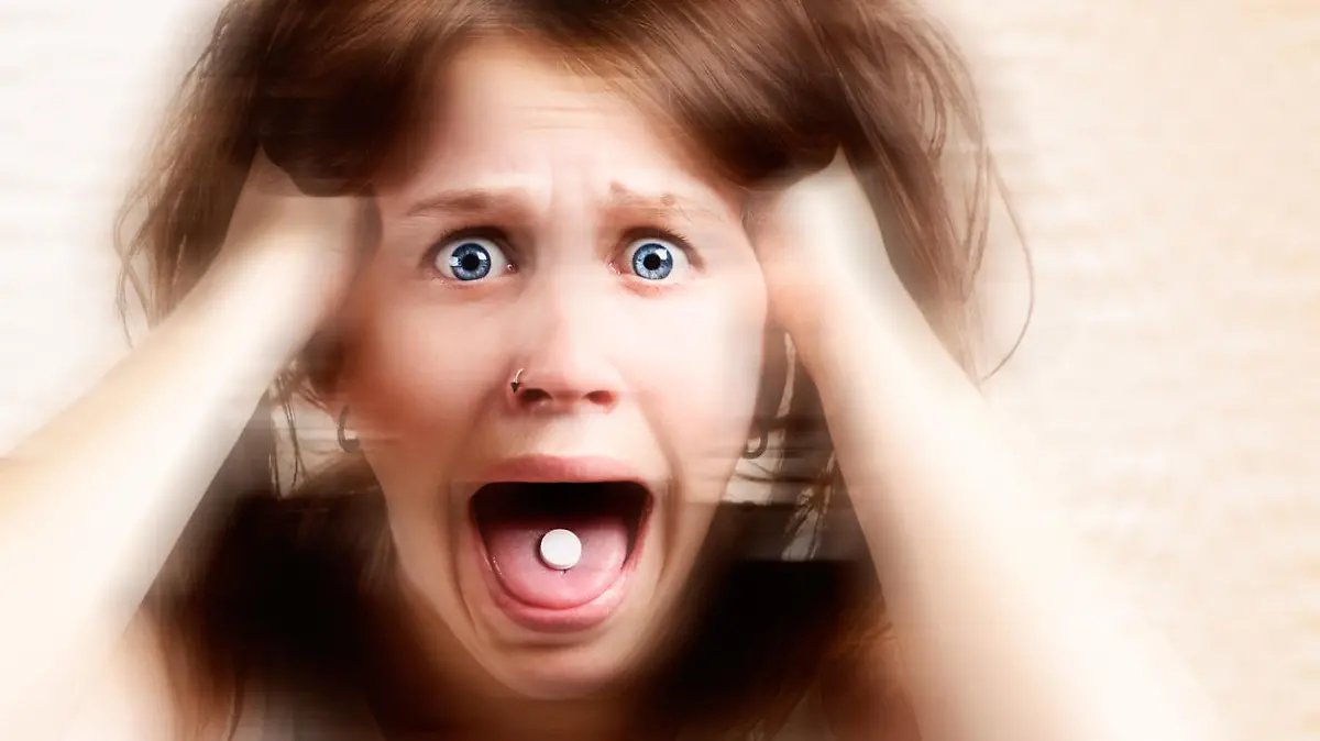 A distorted portrait of a terrified young woman with a pill in her mouth, screaming and tearing her hair out. Symbolizes the horrific results of drug abuse.